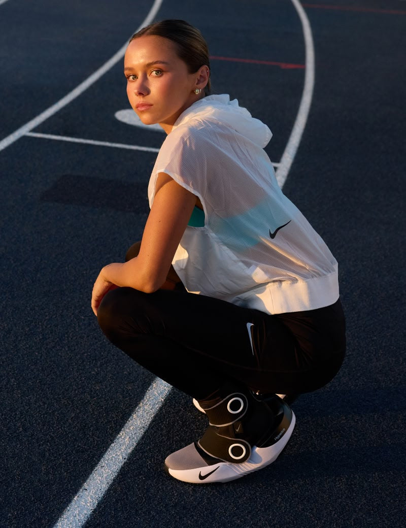 Person in athletic wear in the Nike x Hyperice Hyperboots, posing on a track