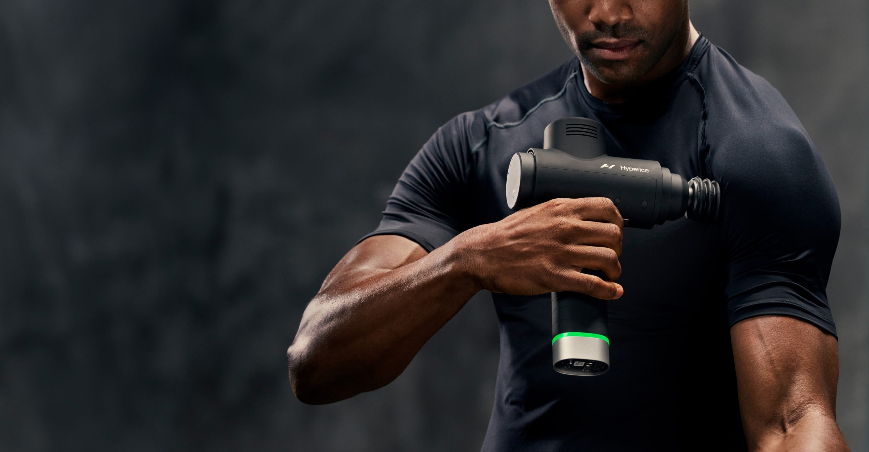 Person using a Hypervolt 2 Pro massage gun on a dark background