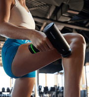 Person using a Hypervolt Go 3 massage gun on their leg in a gym setting