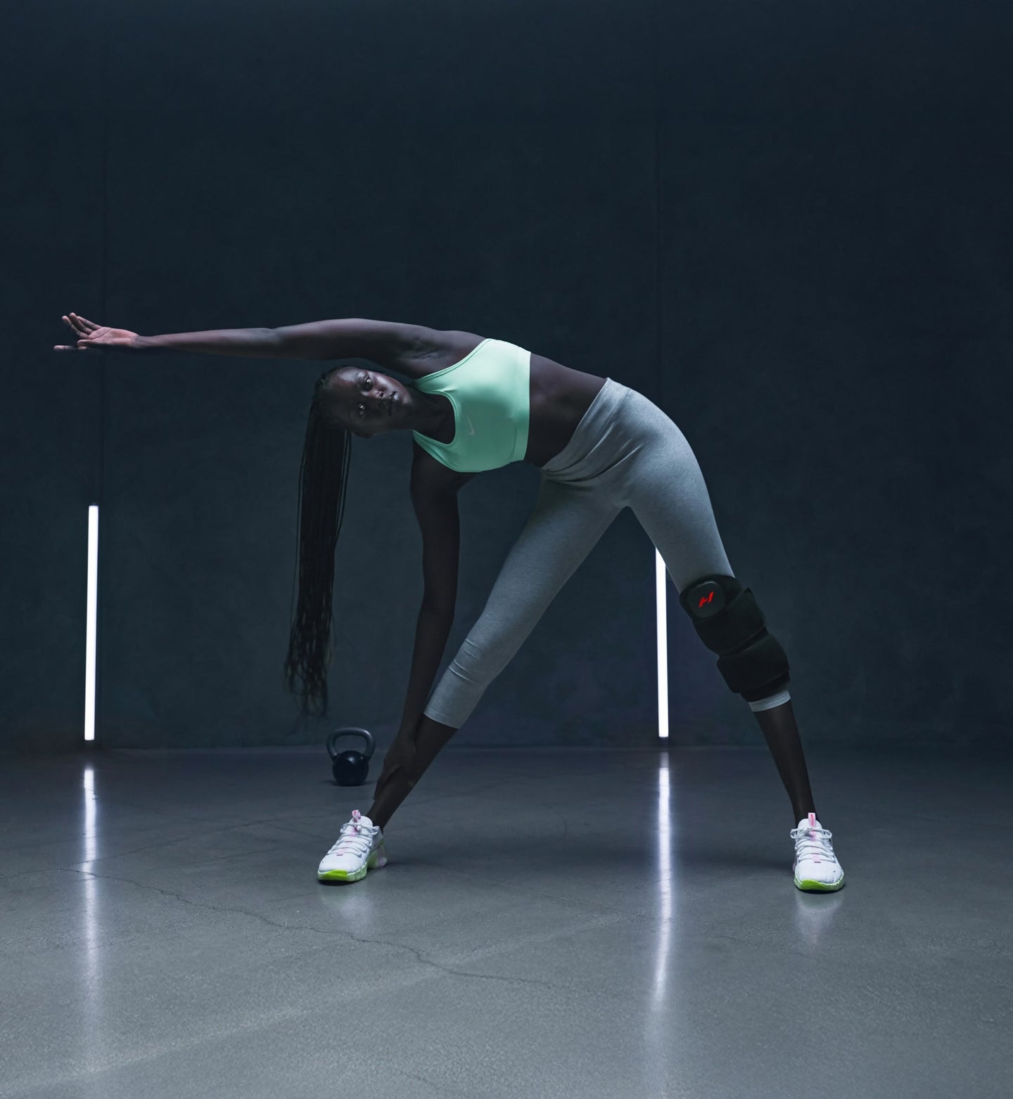 Person in athletic wear wearing a venom leg stretching in a dark studio setting